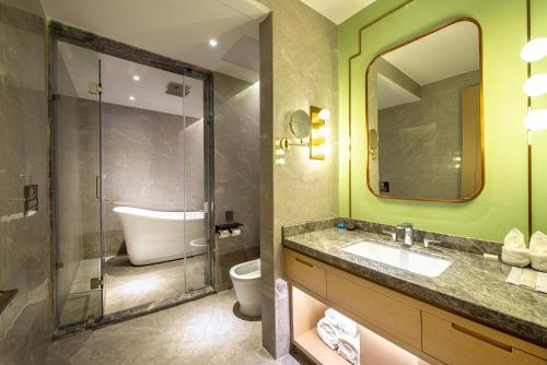 a bathroom with a sink and a toilet and a mirror at Metropolo Jingjiang Hotels- JiangNan market ShuangLong in Guangzhou