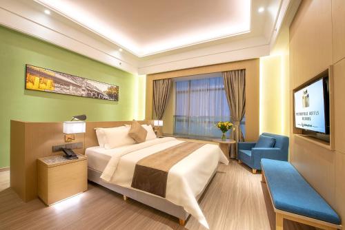 a hotel room with a bed and a tv at Metropolo Jingjiang Hotels- JiangNan market ShuangLong in Guangzhou