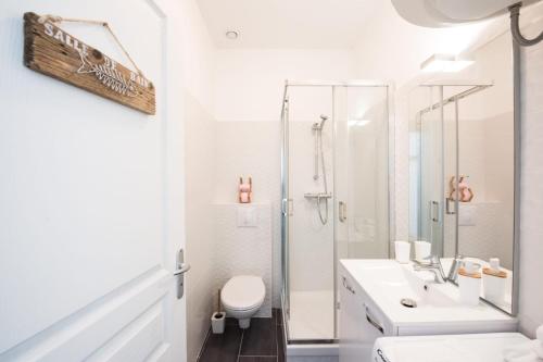 uma casa de banho branca com um chuveiro e um WC. em Le Hirvi - cocon zen et épuré à 10min Vieux Lyon em Lyon
