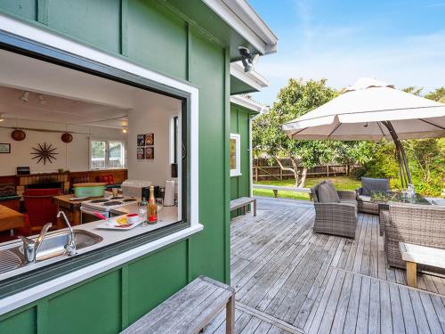 a green house with a kitchen and a patio at Llieno - Lake Taupo Holiday Home in Waitahanui