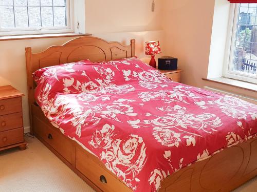 a bedroom with a bed with a red and white bedspread at Rose Cottage in Chard