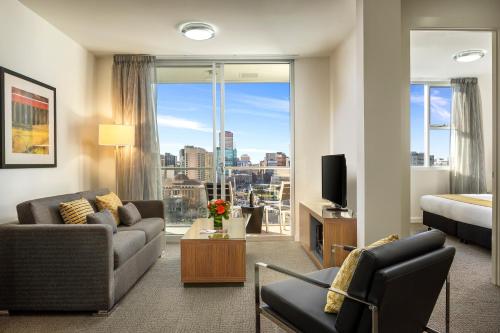 a living room with a couch and a bed and a large window at Quest King William South in Adelaide