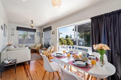 a living room with a white table and chairs at The Black Bach - Mt Maunganui Holiday Home in Mount Maunganui