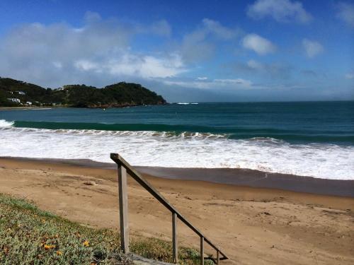 a rail on the beach with the ocean at Shoreside - Tutukaka Holiday Home in Tutukaka