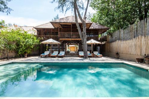 a swimming pool with chairs and a house at The Gili Beach Resort in Gili Trawangan