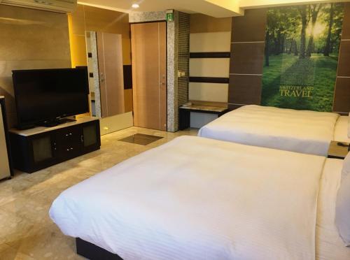 a hotel room with two beds and a flat screen tv at Michelle hotel in Yuanlin
