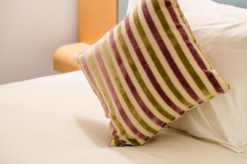 a striped pillow sitting on top of a bed at Hotel Resol Trinity Sapporo in Sapporo