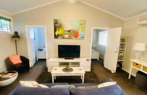 sala de estar con sofá azul y TV en Adelaide Hills Escape, en Woodside