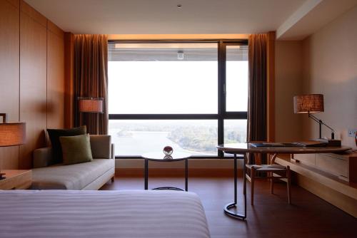 a hotel room with a bed and a couch and a window at Golden Lake Hotel in Jinhu