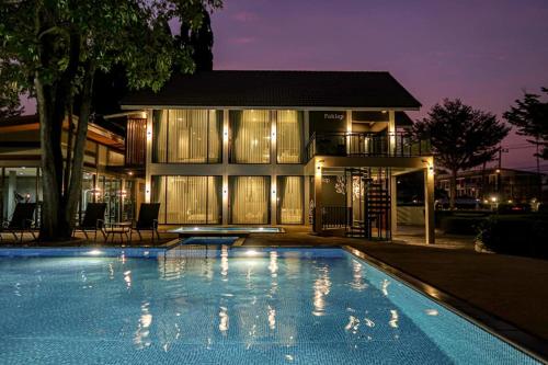 a house with a swimming pool in front of a building at Paklop Resort in Lop Buri