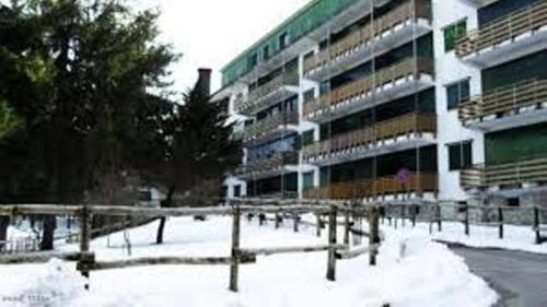 un parcheggio coperto di neve di fronte a un edificio di appartamento Prato Verde I a Pescasseroli