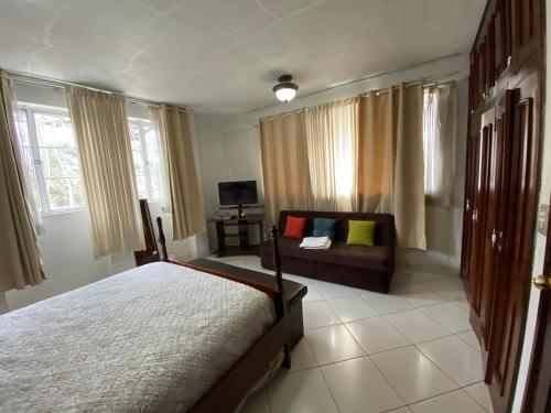 sypialnia z łóżkiem i kanapą w obiekcie Apartamentos Comodos Cerca del Aeropuerto w mieście Gwatemala