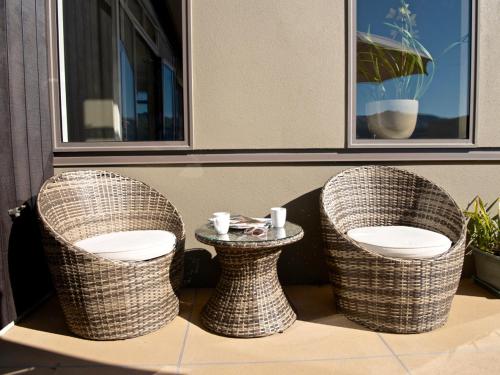 two wicker chairs and a table on a patio at Kotare Point Paradise - Akaroa Holiday Home in Akaroa