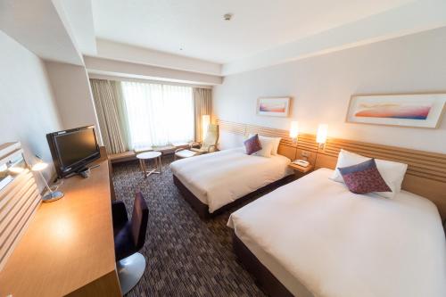 a hotel room with two beds and a television at Hotel Resol Trinity Sapporo in Sapporo