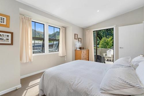 a white bedroom with a large bed and windows at Lavender Country Cottage - Arrowtown Holiday Home in Arrowtown