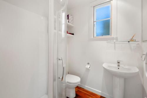 a white bathroom with a toilet and a sink at North Cole Cottage - Hatepe Lake Front Home in Waitahanui
