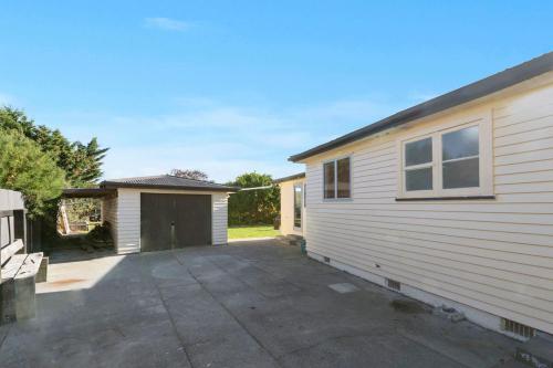 a white building with a garage next to a house at 30 Cologne - Martinborough Holiday Home in Martinborough 