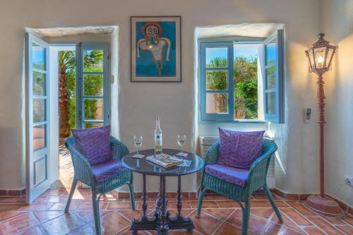 a room with a table and chairs and windows at Morro dos Anjos - authentic farmhouse with a view just 3km from Olhao in Olhão