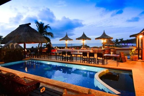 a resort with a swimming pool and tables and umbrellas at Golden Point Resort in Rakiraki