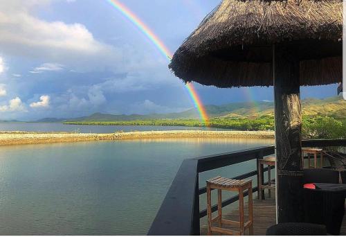 a rainbow over the water with a table and chairs at Golden Point Resort in Rakiraki