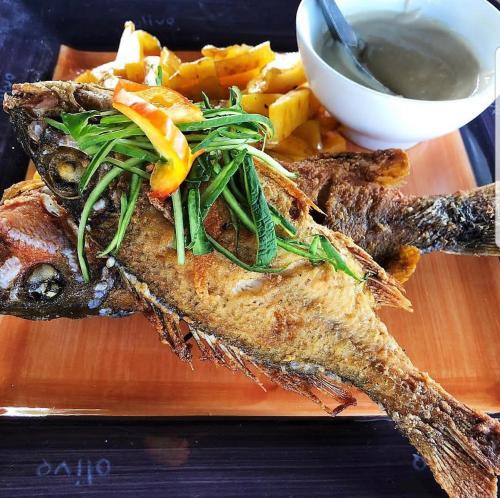 a plate of food with fish and chips and sauce at Golden Point Resort in Rakiraki