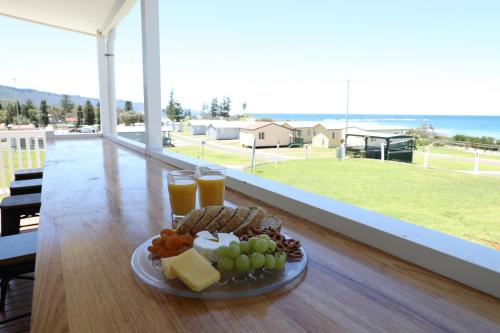 einen Teller mit Käse und Obst auf einem Tisch mit Aussicht in der Unterkunft Bulli Beach Tourist Park in Bulli