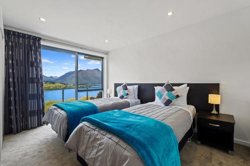 two beds in a room with a large window at Queenstown Lake Views - Downstairs Apartment in Queenstown