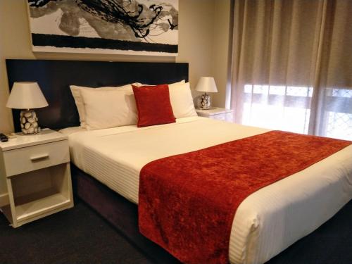 a bedroom with a large bed with a red blanket at Apartments on Chapman in Melbourne