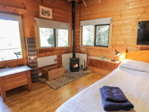a bedroom with a bed and a woodburning stove at The Log Cabin in Kilmore