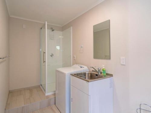 a white bathroom with a sink and a shower at Town Centre Treat - Tairua Holiday Home in Tairua