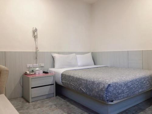 a bedroom with a bed and a phone on a table at Ruei Gung Business Hotel Kaohsiung in Kaohsiung