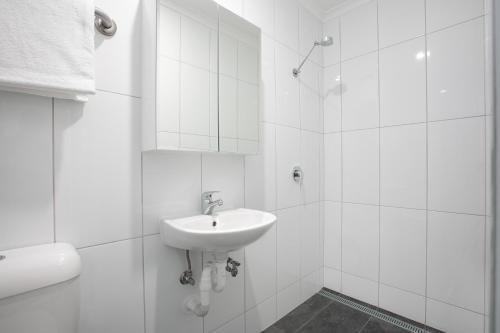 a white bathroom with a sink and a mirror at MiHaven Shared Living - Martyn St in Cairns