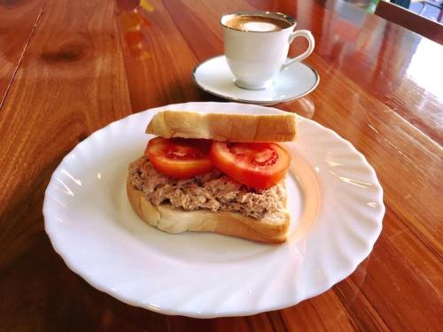 a sandwich on a white plate with a cup of coffee at Urban Hostel Bangkok in Bangkok