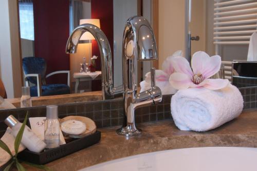 a bathroom counter with a sink with a pink flower at Villa Ludwig Suite Hotel in Hohenschwangau