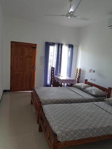a bedroom with two beds and a table and window at JEYs Place in Nilaveli