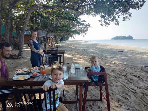 a family sitting at a table on the beach at Koh Jum Delight Beach in Ko Jum
