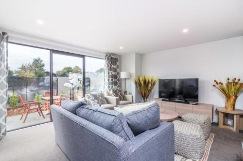 a living room with a blue couch and a tv at Restful in Riccarton - Christchurch in Christchurch