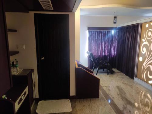 a living room with a black door and a chair at Sri Gnana Vedha Beach Residency in Velānganni