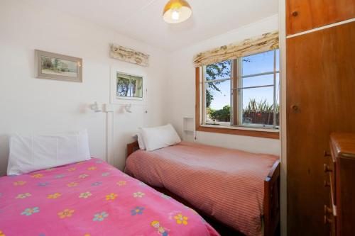 a bedroom with two beds and a window at North Cole Cottage - Hatepe Lake Front Home in Waitahanui