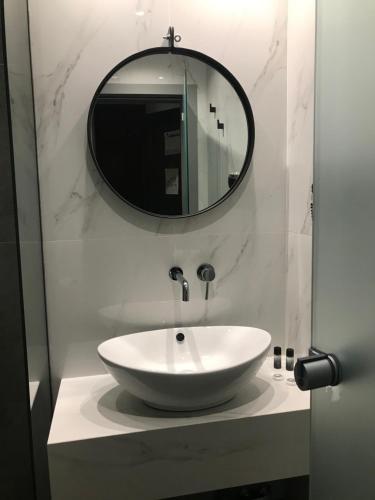 bagno con lavandino bianco e specchio di Anessis a Salonicco