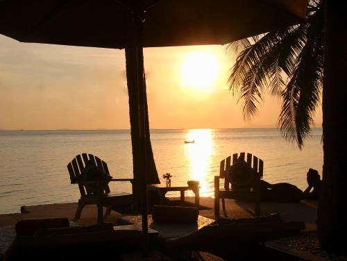 two chairs and a table on the beach at sunset at Sibaja Palms Sunset Beach Luxury Apartments in Taling Ngam Beach