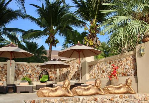 a group of goldulptured people sitting under umbrellas at a resort at Sibaja Palms Sunset Beach Luxury Apartments in Taling Ngam Beach