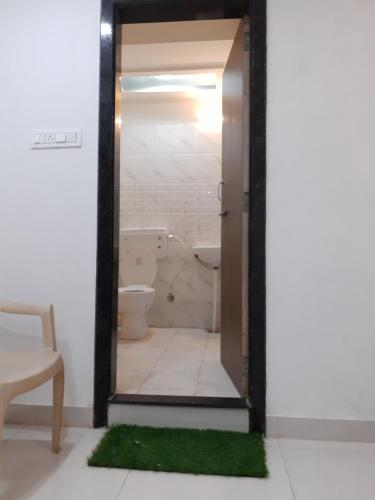 a bathroom with a toilet and a door with a green rug at Benda Rejuvenate Hotel in Jodhpur