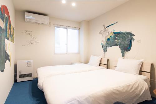 two beds in a room with a painting of a donkey on the wall at torune in Sapporo