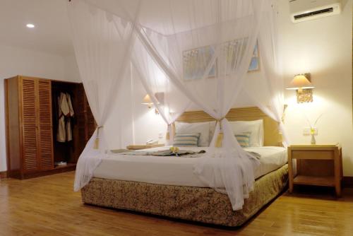 a bedroom with a white bed with a canopy at Seminyak Paradiso Hotel in Seminyak