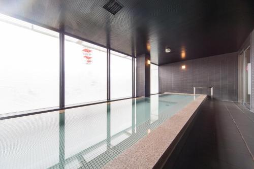 a large swimming pool in a building with windows at Hotel Resol Trinity Sapporo in Sapporo