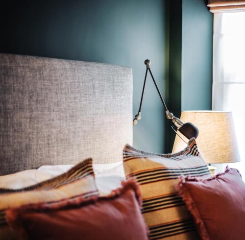 a bedroom with a bed with a lamp and pillows at Blonde Hedgehog in Alderney