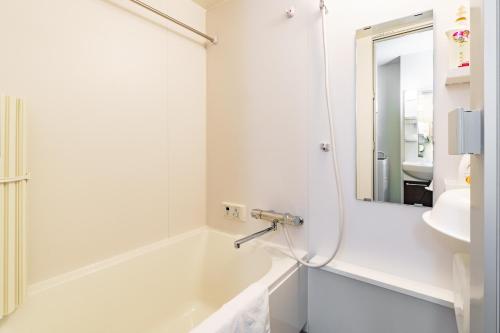 a white bathroom with a tub and a sink at IKIDANE Residential Hotel SHIMANOUCHI in Osaka