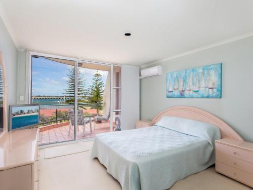 a bedroom with a bed and a large window at Castillo Del Mar 10 in Tuncurry