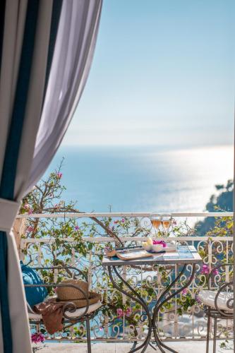 a table on a balcony with a view of the ocean at Positano Art Hotel Pasitea in Positano